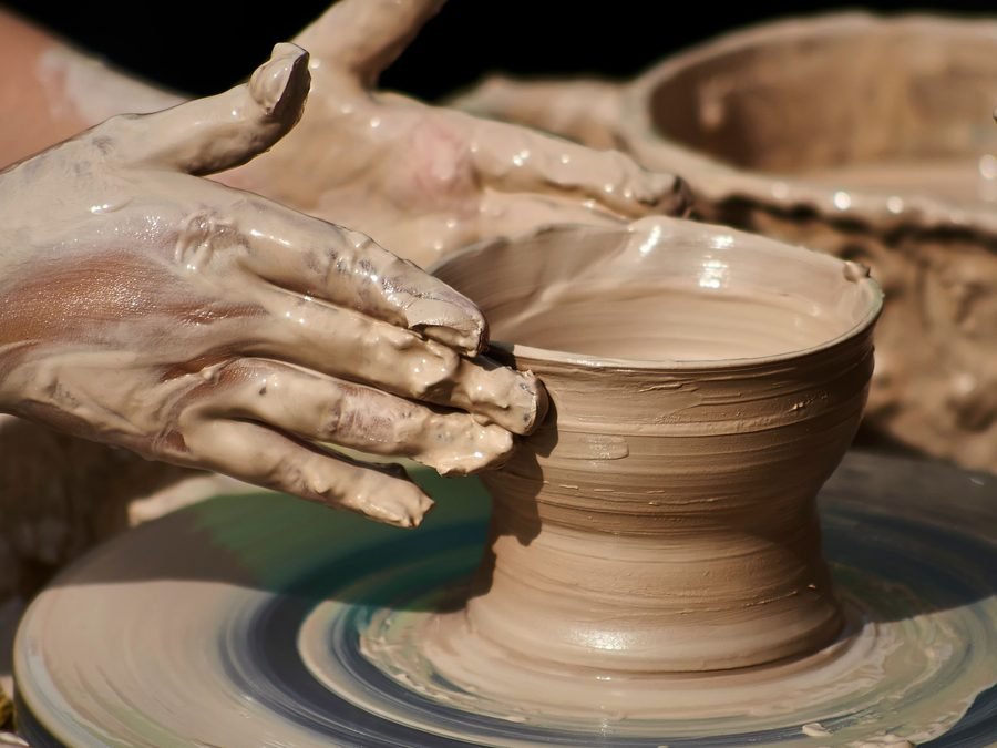 An artisan's clay-covered hands mid-work